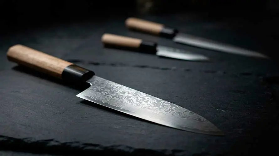 Cuchillos Deba de diferentes tipos sobre una tabla de cortar oscura