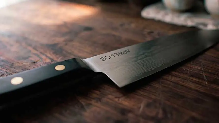 Cuchillo de acero 8Cr13MoV sobre tabla de corte de madera
