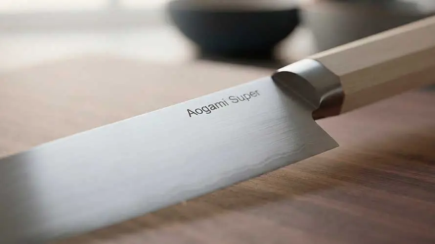 Cuchillo de acero Aogami Super sobre una tabla de corte de madera