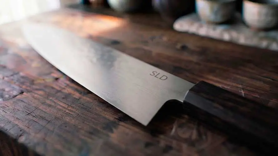 Cuchillo de acero SLD sobre una tabla de corte de madera