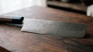 Cuchillo nakiri sobre tabla de madera oscura en una bonita cocina