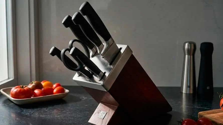 Un taco de cuchilos en una bonita cocina decorada con tomates en la encimera